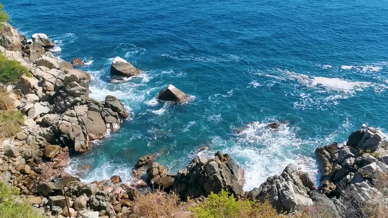 冲浪浪蓝绿色的水岩石悬崖巨石埃斯孔迪多港。视频素材