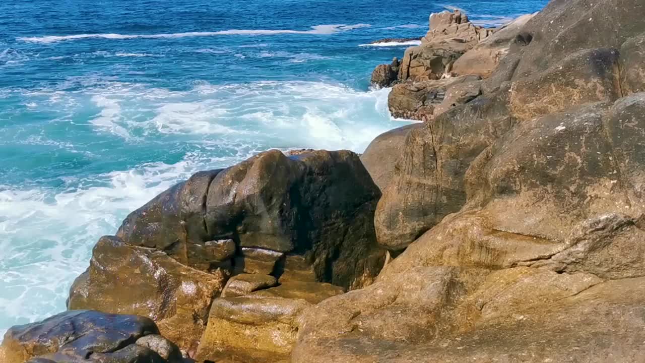 冲浪浪蓝绿色的水岩石悬崖巨石埃斯孔迪多港。视频素材