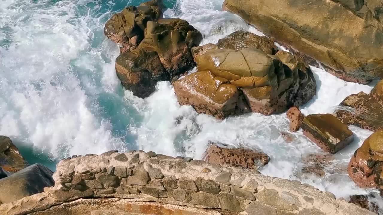 冲浪浪蓝绿色的水岩石悬崖巨石埃斯孔迪多港。视频素材