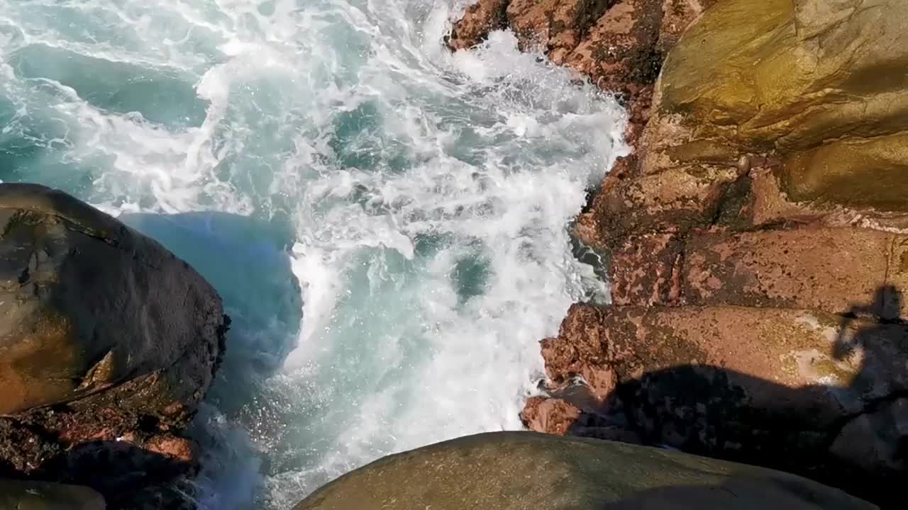 冲浪浪蓝绿色的水岩石悬崖巨石埃斯孔迪多港。视频素材