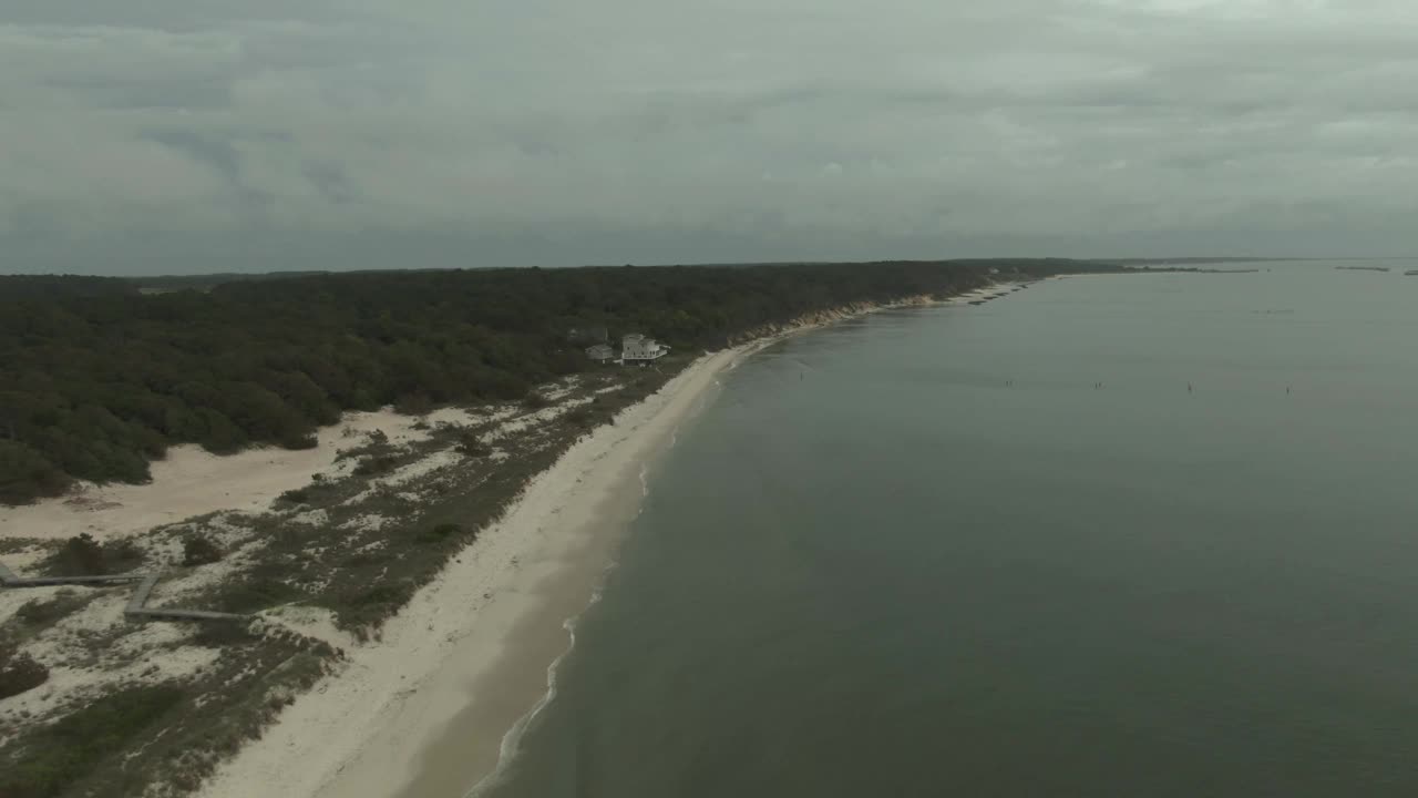 在多云的日子里，从高空拍下东海岸海滩、树木和白色的海滨别墅，以平面色彩剖面拍摄。视频素材