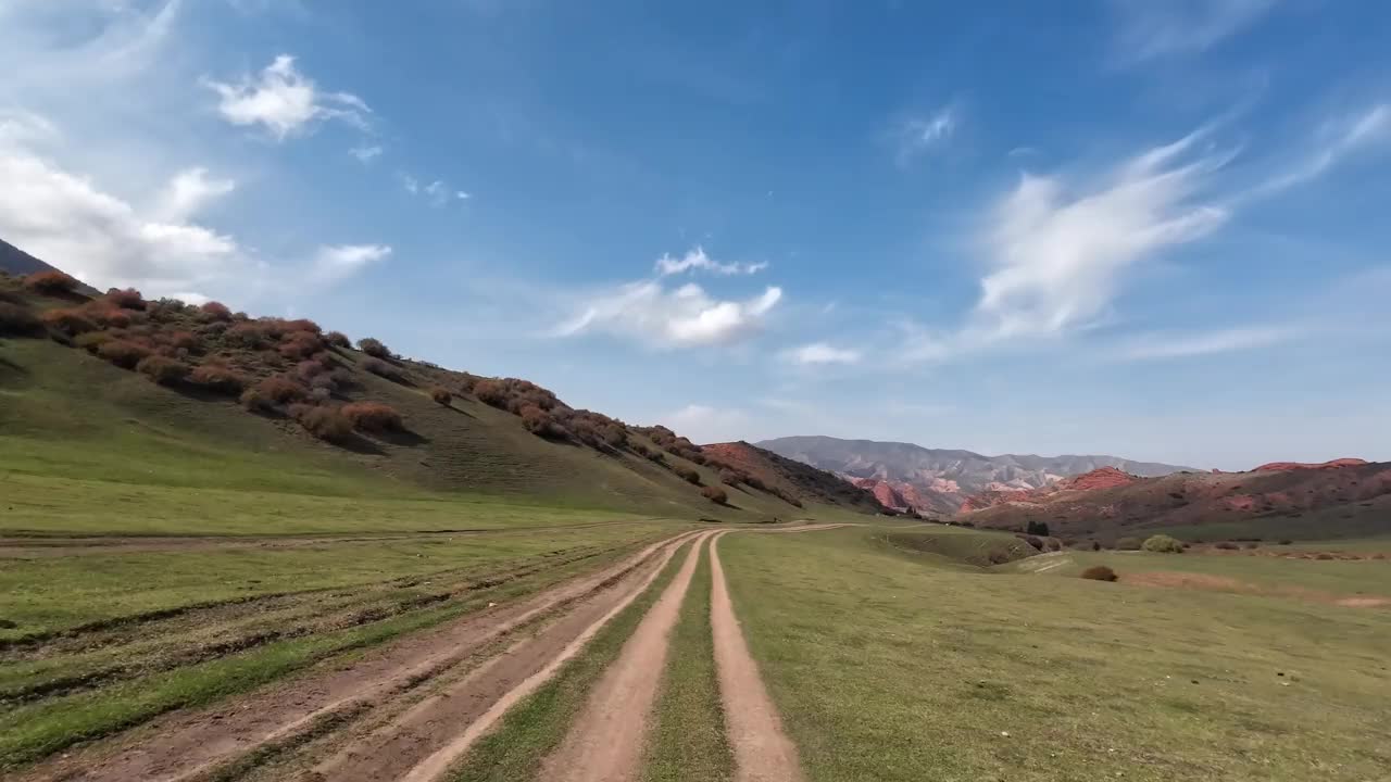 秋天，沿着红色岩石中的绿色山谷走在土路上视频素材