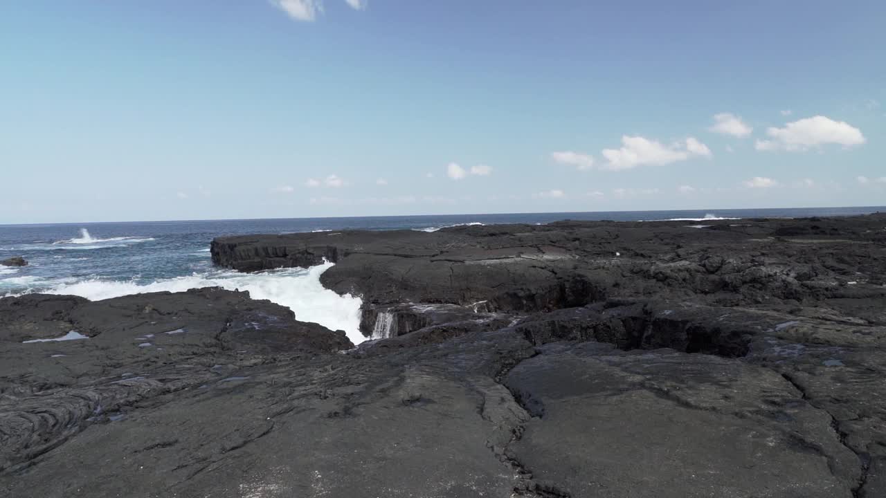 在一个阳光明媚的日子里，深蓝色的太平洋海浪冲击着加拉帕戈斯群岛的黑色火山熔岩。视频素材