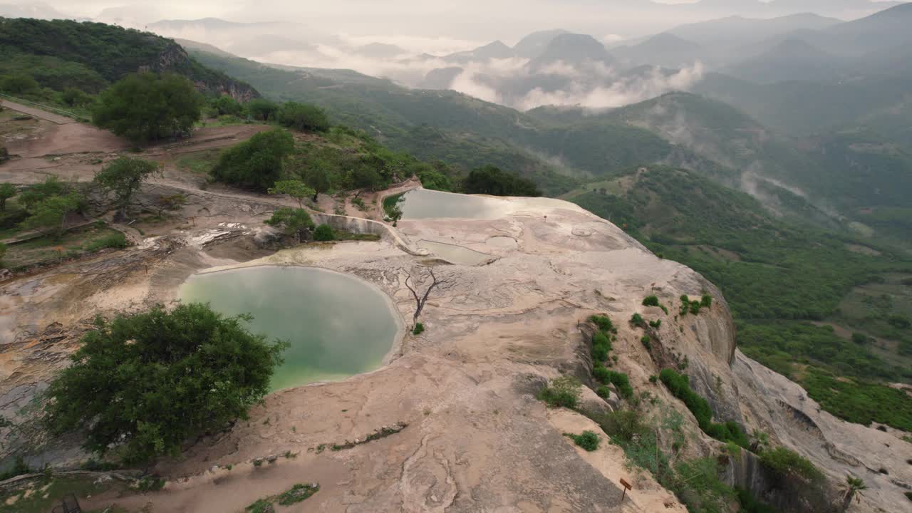 空中无人驾驶飞机在山上拍摄，经过水体，显示出茂密的森林，远处的山白云视频素材