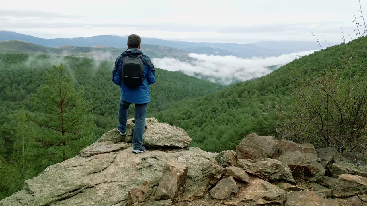 一名徒步旅行者爬上一块岩石，凝视着马德里瓜达拉马山上美丽的风景。视频素材