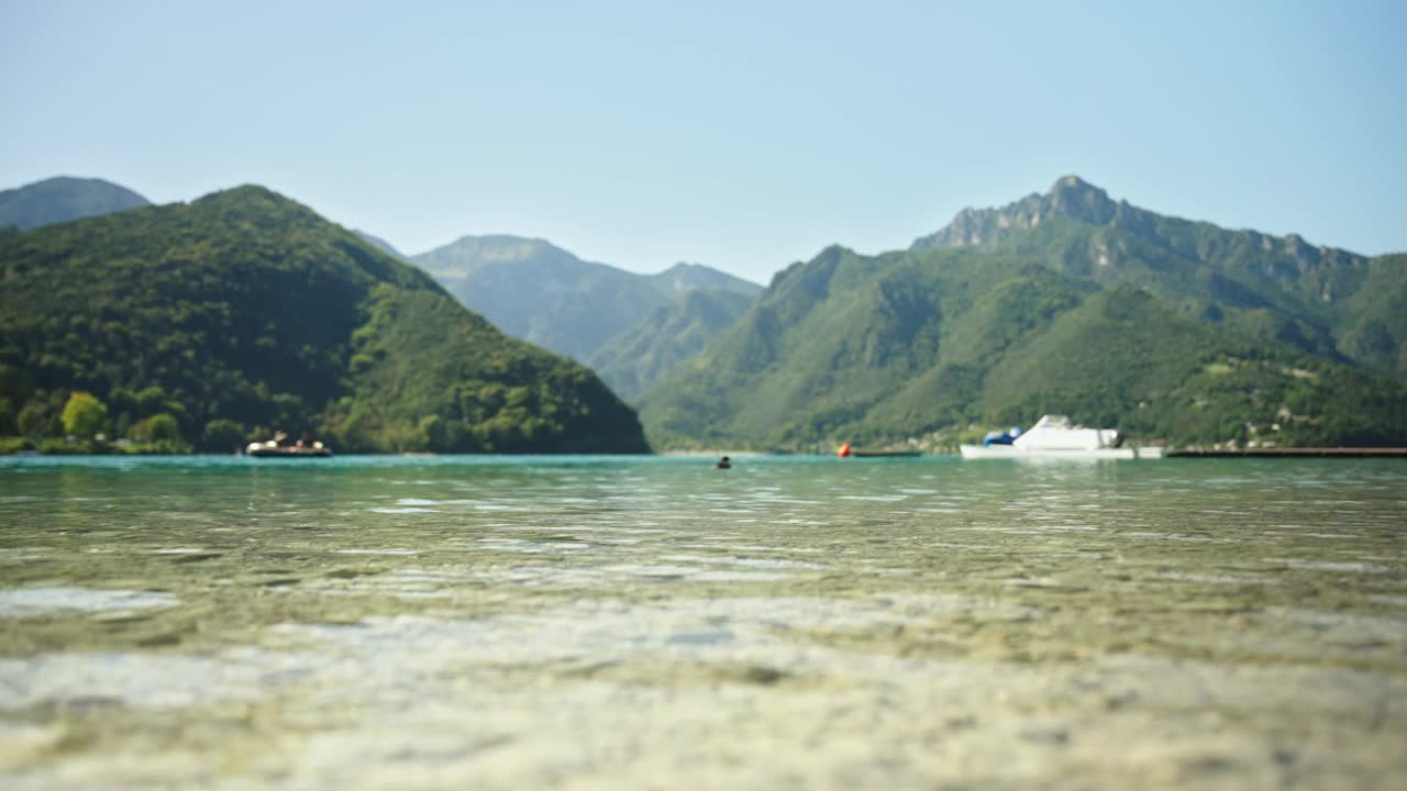 平静的加尔达湖与雄伟的山脉在晴天晴空下的表面水平视频素材