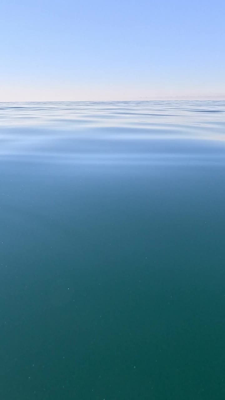 海水表面垂直鸟瞰图，相机飞过清澈的海水。太阳眩光。抽象航海夏季海洋自然。度假、度假、旅游的概念。没有人。天气和气候变化视频素材