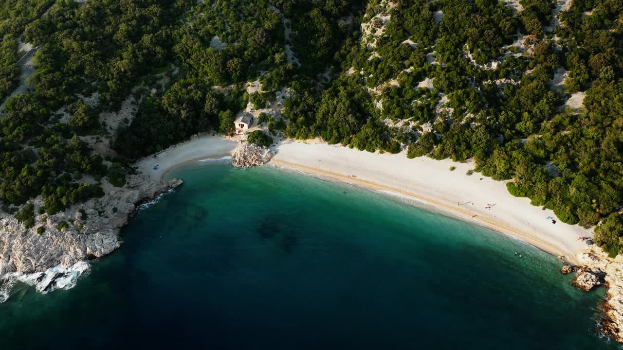 在克罗地亚的Lubenice海滩，美丽的泻湖，海浪拍打着白色的沙滩，无人机倾斜着降落视频素材