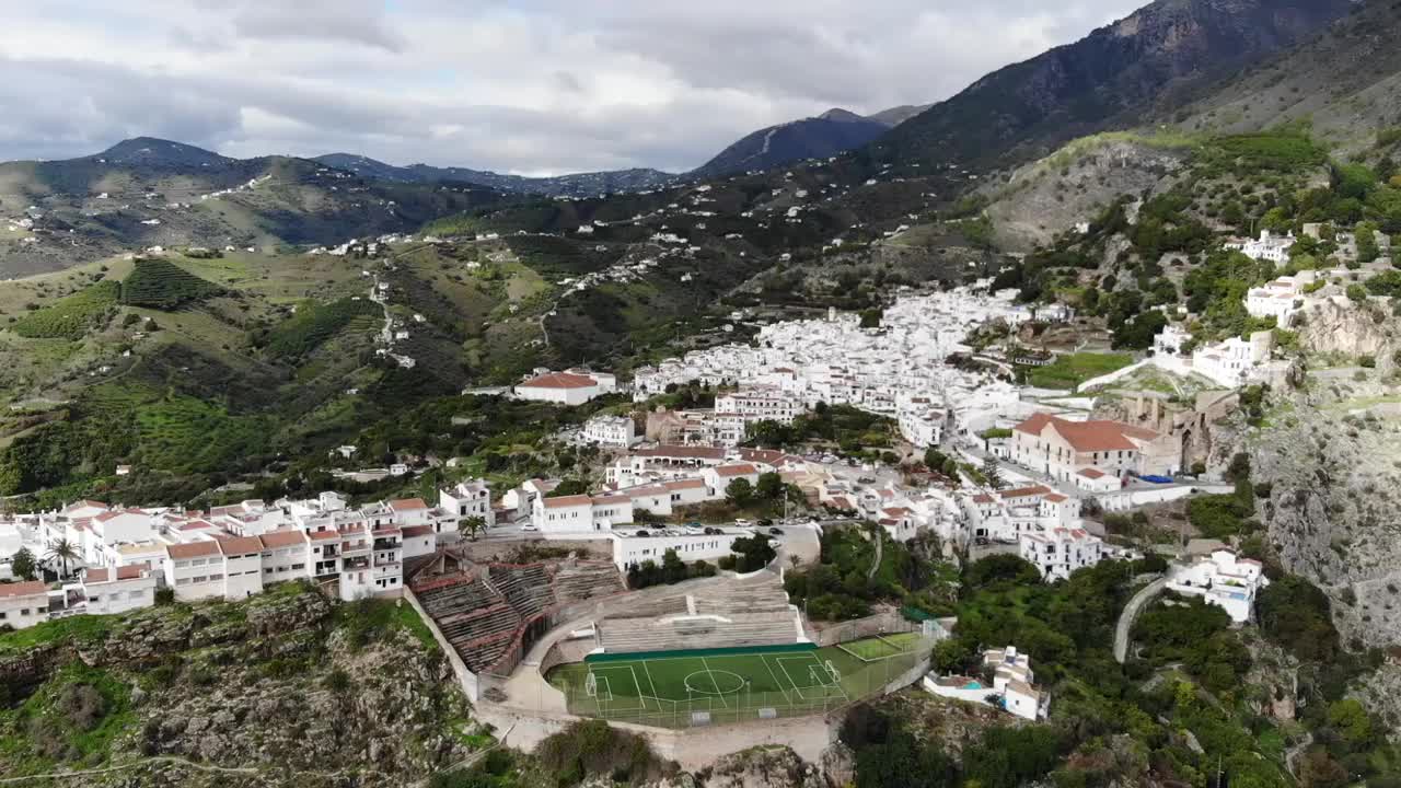 空中飞行可俯瞰弗里吉利亚纳白色村庄的丘陵和安达卢西亚山地景观，突出足球场。西班牙视频素材