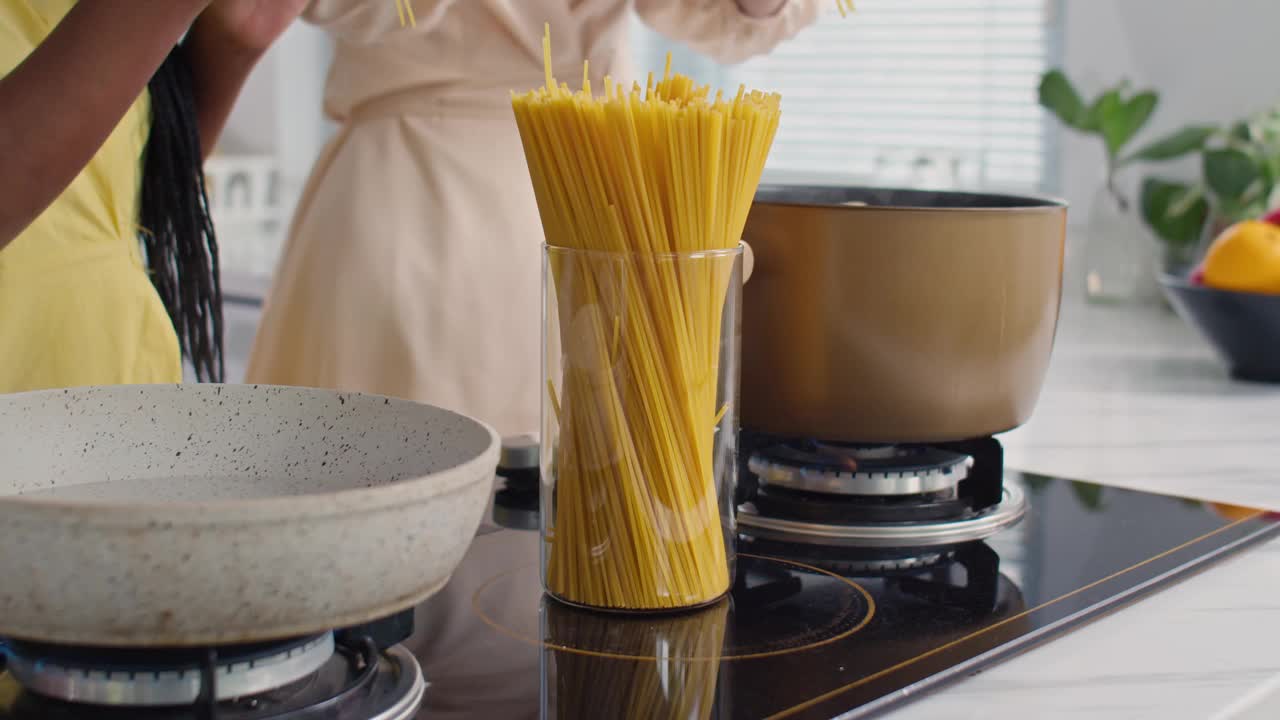 年轻的多民族女孩为晚餐烹饪意大利面视频素材