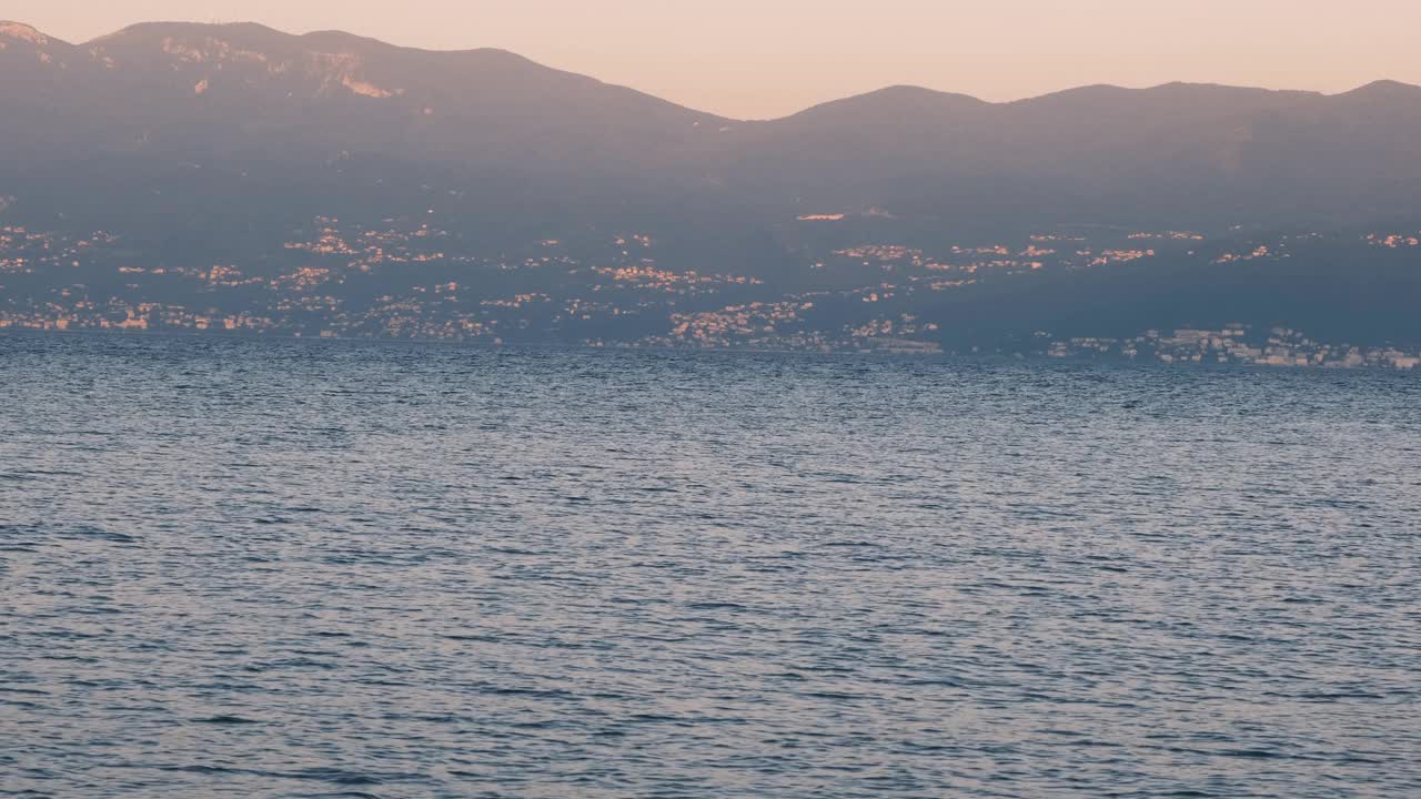 美丽的海景，可以看到清晨的大海和山脉，背景是小村庄。4k视频拍摄。视频下载