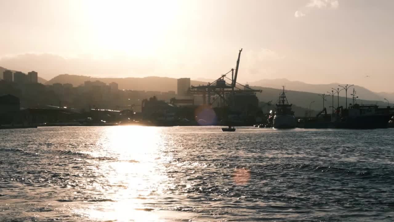 里耶卡港口阳光明媚的海景，过去的老起重机点缀着全景，背景是摩天大楼。海洋的景象与一艘渔船在浩瀚的大海。视频下载