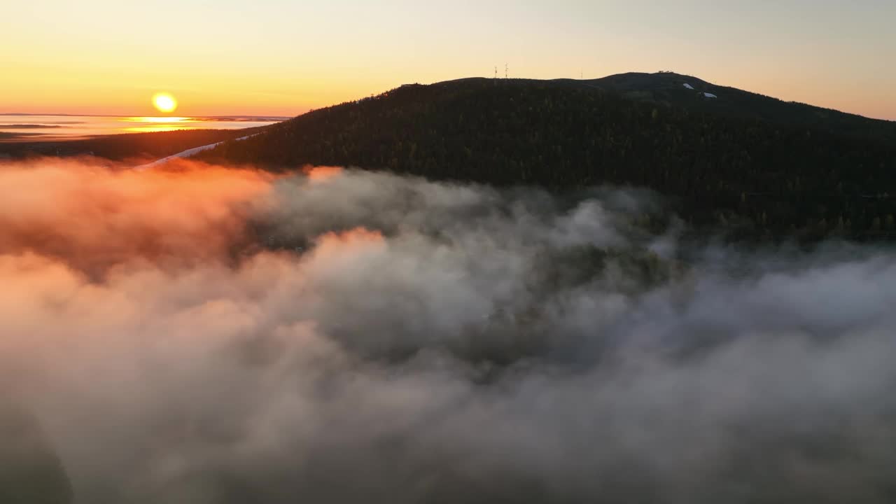 从空中俯瞰，在迷雾笼罩的山谷上空盘旋，背景是莱维顿图里，拉普兰的日出视频素材