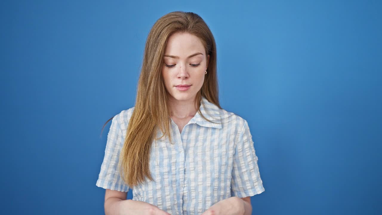 年轻的金发女子微笑自信地拿着验孕棒在孤立的蓝色背景视频素材