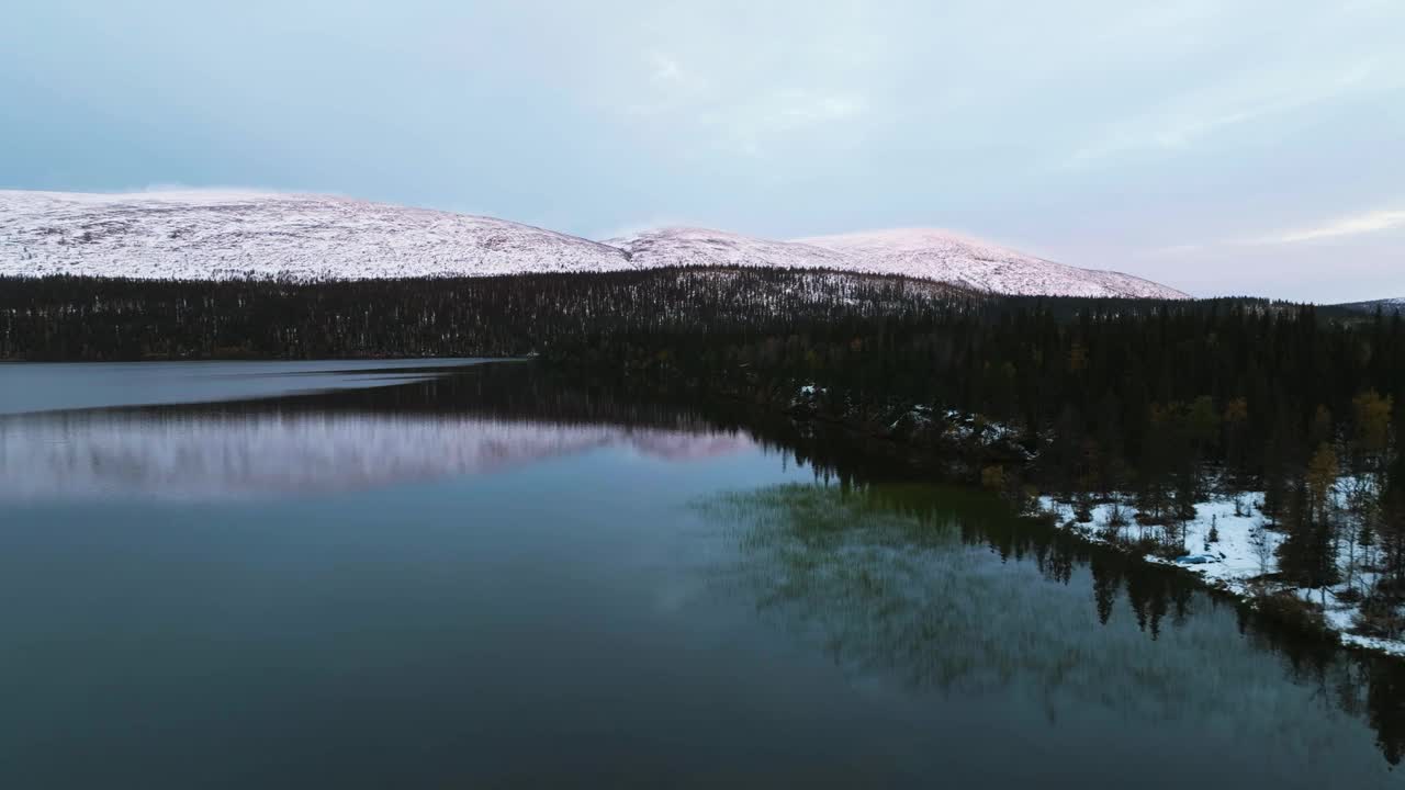 鸟瞰图在一个反射湖与雪山背景，秋天日落在拉普兰视频素材