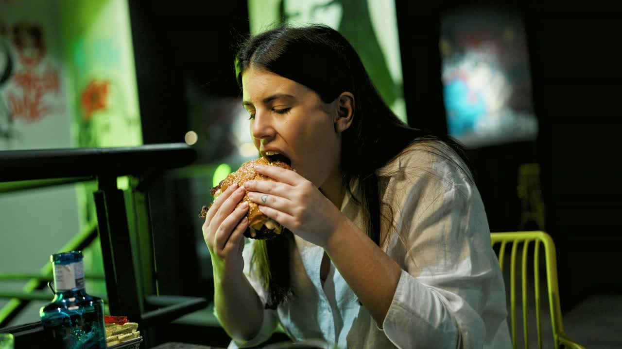 年轻漂亮的西班牙女人在餐厅吃美味的汉堡视频素材