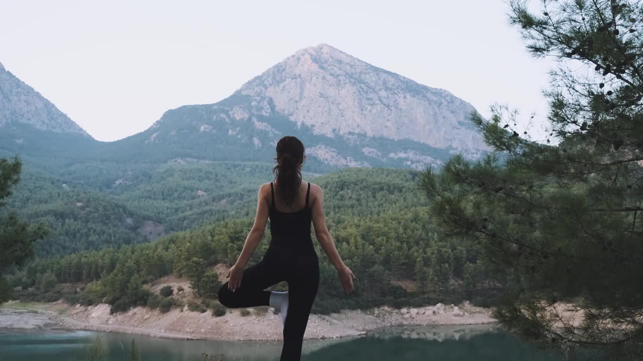 年轻女子在山的背景上以莲花姿势练习瑜伽视频下载