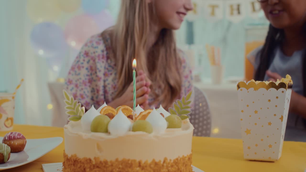 女孩在餐桌上吹灭生日蛋糕上的蜡烛视频素材