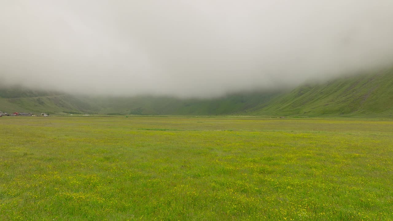 飞过绿色的草原，飞向挪威云雾缭绕的高山。——空中视频素材