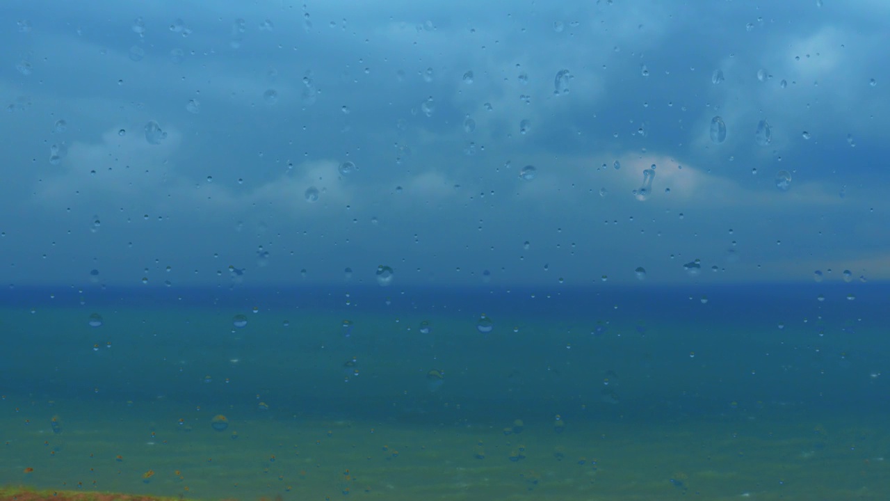 玻璃窗，海景。深海。地平线上乌云密布。风暴警告。雨滴滴落的特写镜头。水从窗户流下来。天气预报。远处乌云密布。视频素材