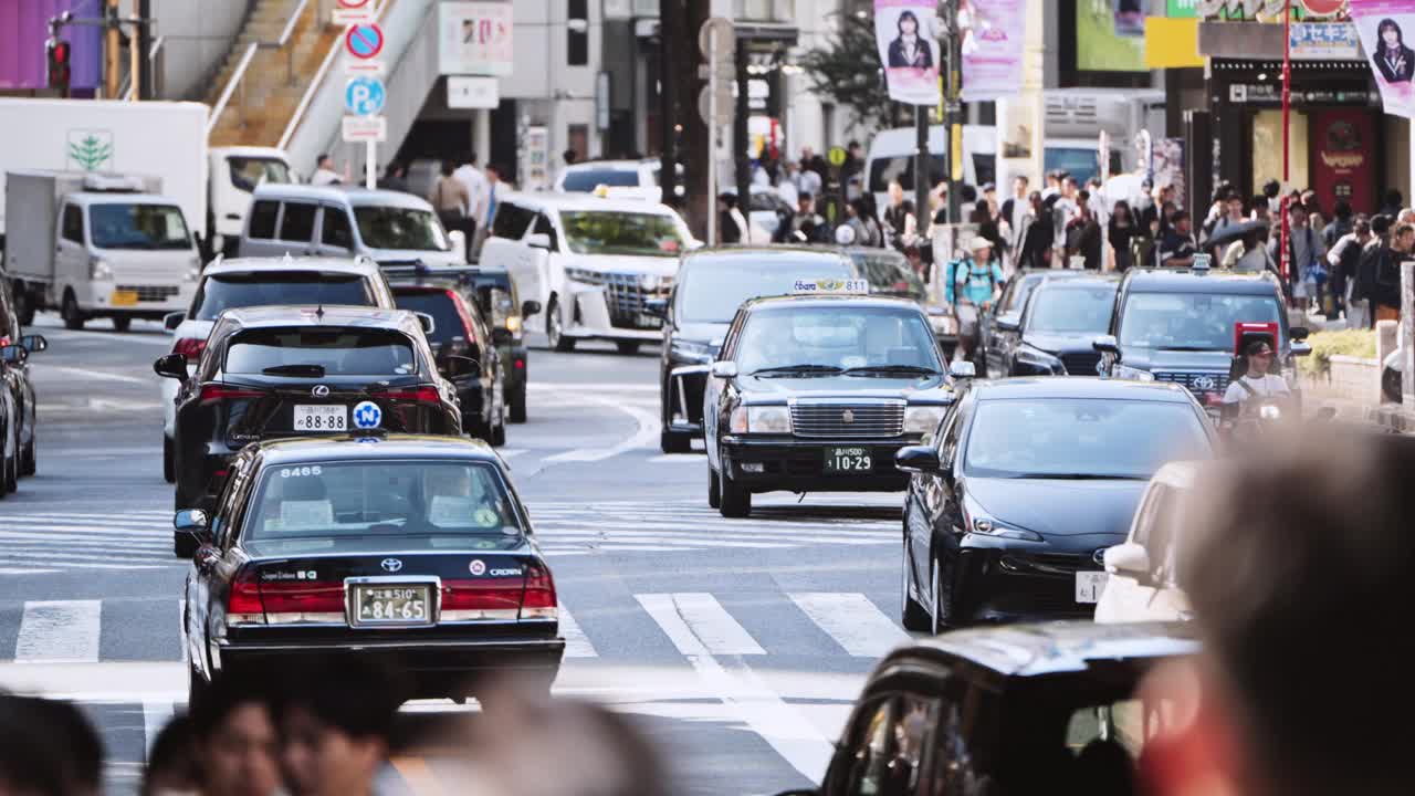 在日本东京涩谷十字路口的道路上，成群的亚洲人步行、汽车、公交车、出租车等交通工具。日本通勤文化生活方式，旅游旅游地标，亚洲交通，城市生活视频下载