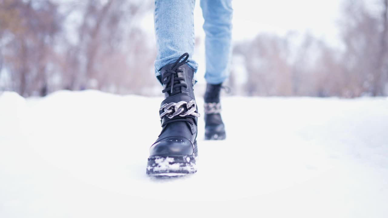 冬天下雪的公园里行走的女性腿特写。冬日里行走的女人。腿上穿着黑色的冬靴。积极的生活方式。视频素材