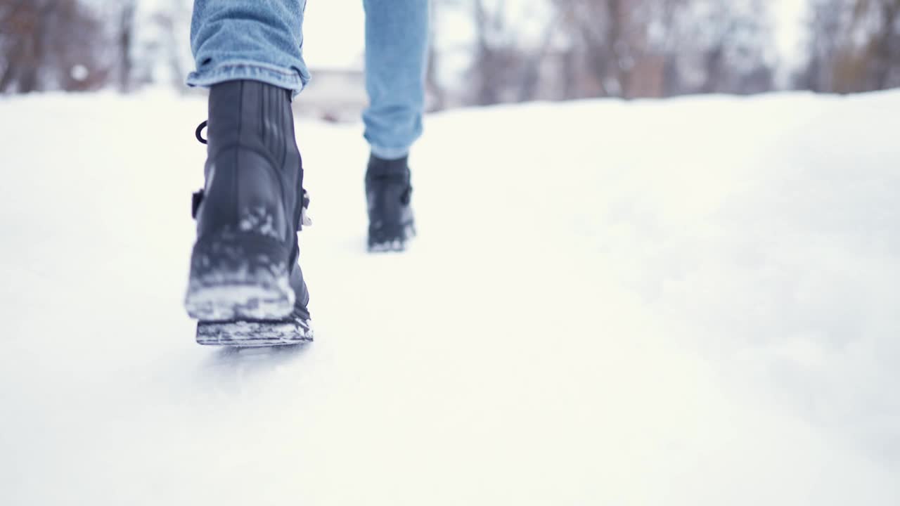 冬天下雪的公园里行走的女性腿特写。冬日里行走的女人。腿上穿着黑色的冬靴。积极的生活方式。视频素材