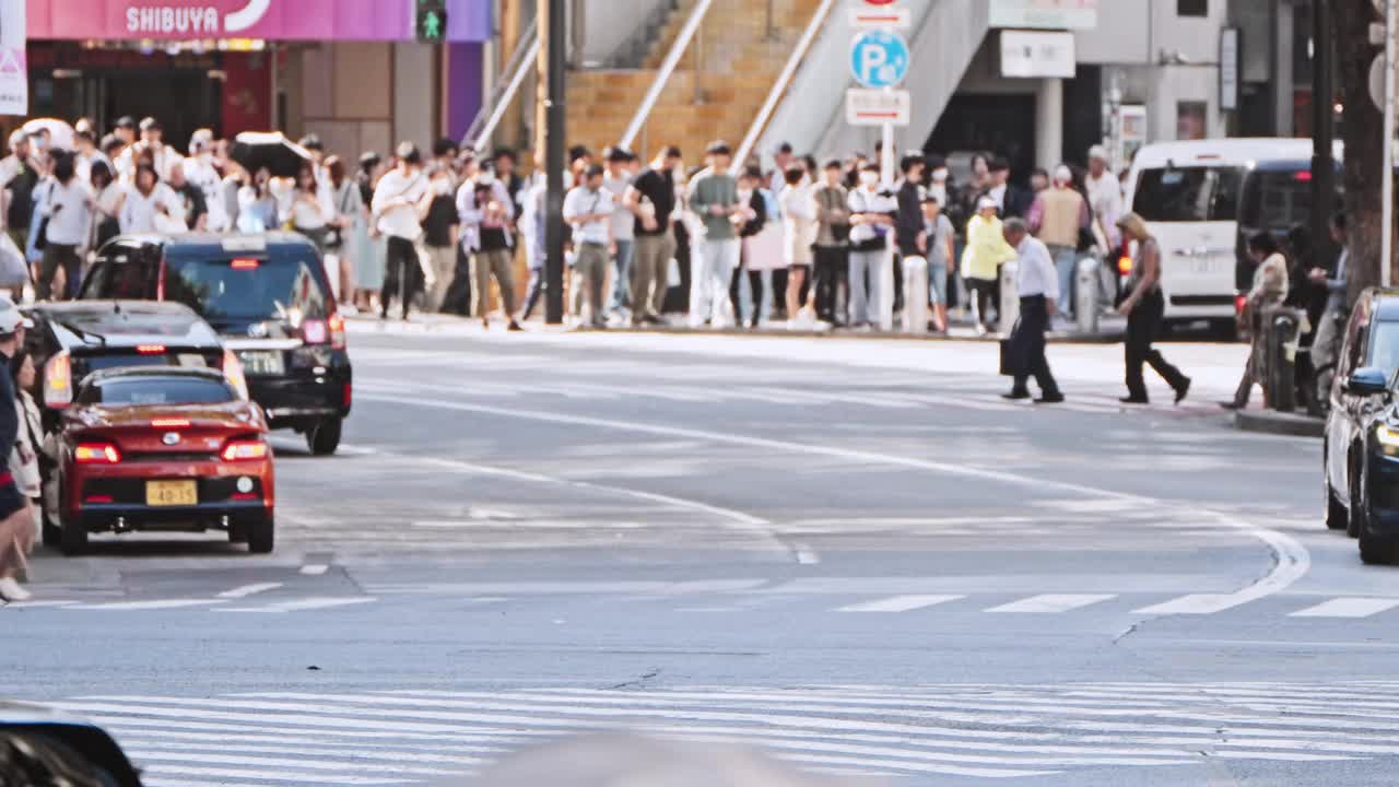 在日本东京涩谷十字路口，一群亚洲人穿过马路，汽车交通。日本通勤文化生活方式，旅游旅游地标，亚洲交通，城市生活理念视频下载