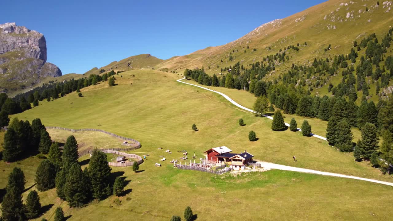 空中，晴天。意大利多洛米蒂的小屋。无人机全景雄伟的岩石山脊和绿色牧场，意大利。视频素材