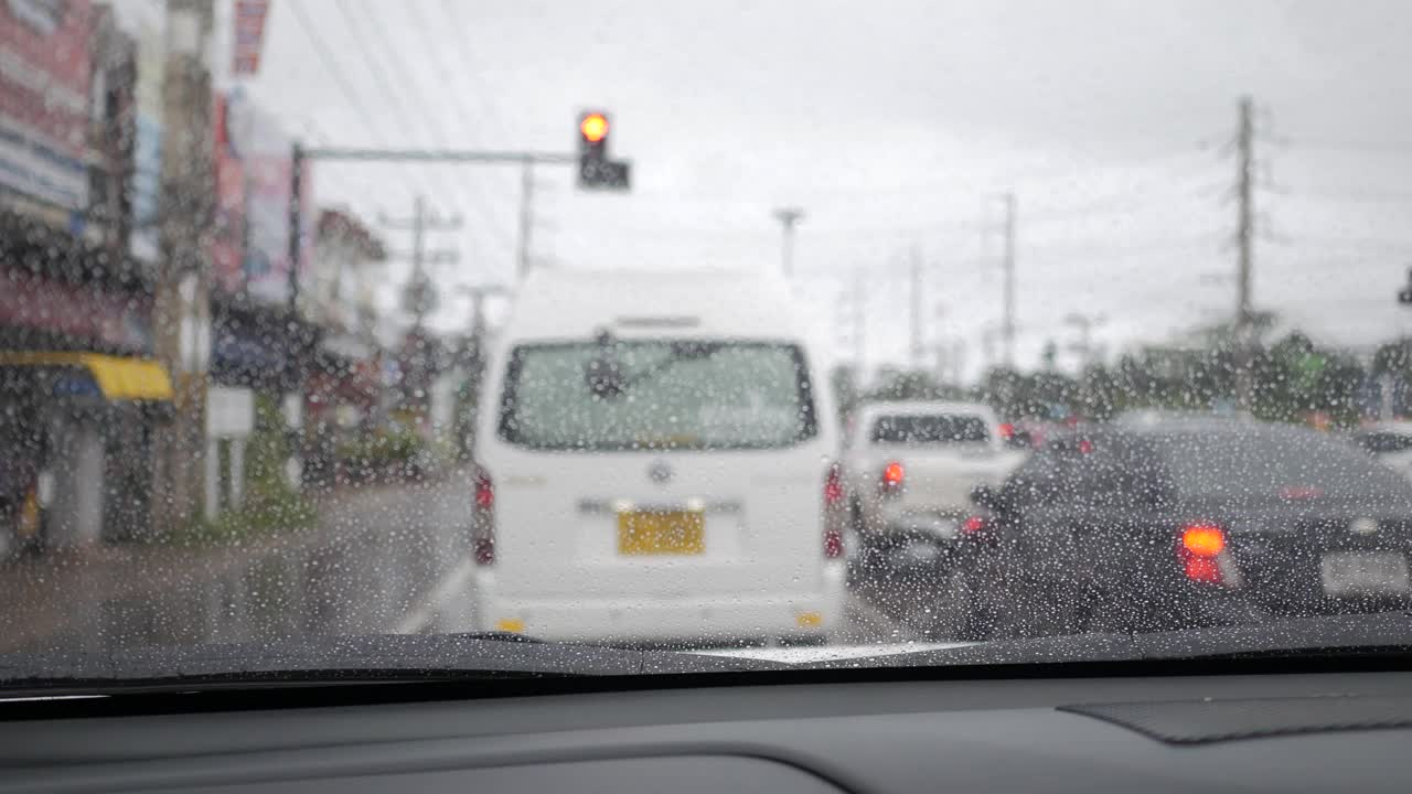 从车内看，雨水打在汽车玻璃上。在交通拥挤的街道上开车。视频素材