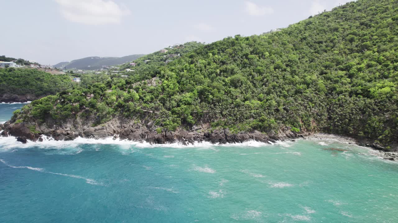 圣托马斯USVI美丽的空中全景，蓝色的绿松石水在悬崖上的岩石上撞击，背景是雾屋山，悬崖上的绿色树木视频素材