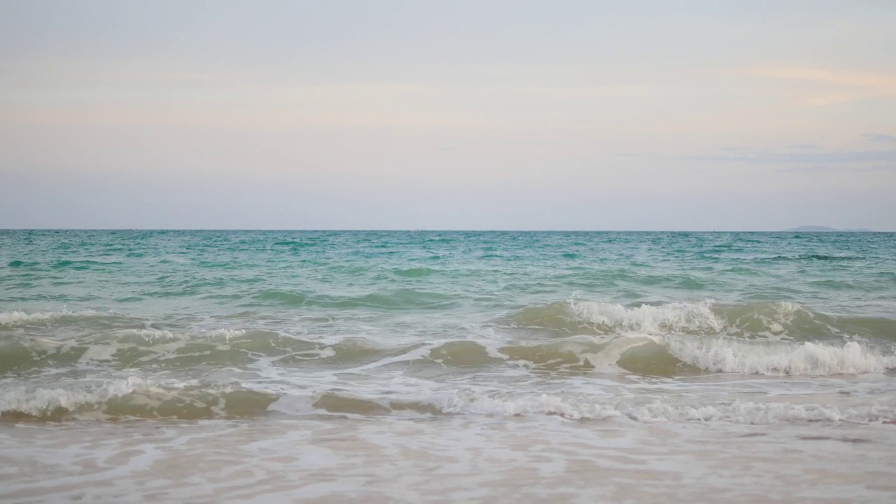 泡沫滚滚的海浪涌向白色的沙滩。海浪拍打着沙滩。视频下载