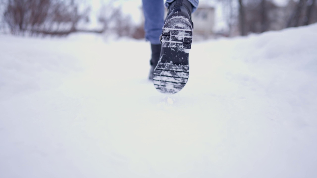 冬天下雪的公园里行走的女性腿特写。冬日里行走的女人。腿上穿着黑色的冬靴。积极的生活方式。视频素材