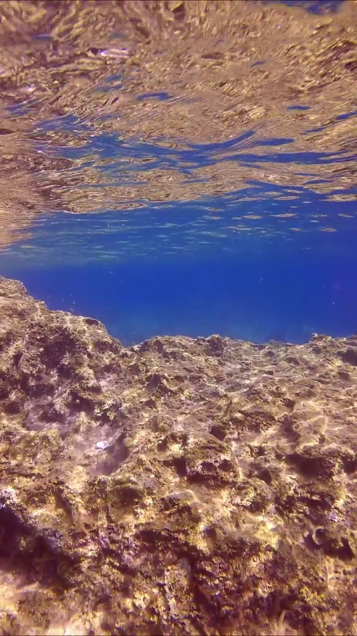 水下海岸岩石蓝水背景，慢动作视频素材