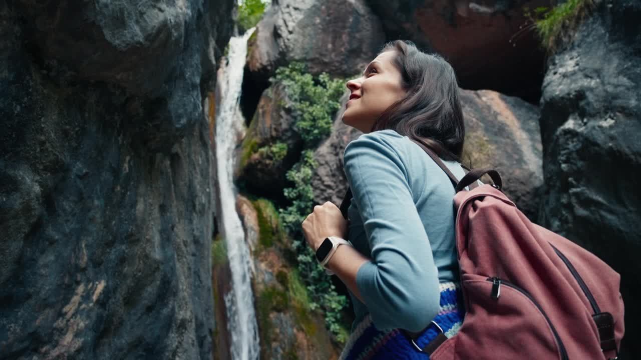 背包客在山间小径徒步旅行时欣赏美丽的瀑布视频下载