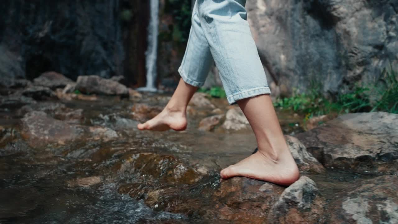 镜头跟随赤脚游客沿着山河和瀑布走在岩石上视频素材