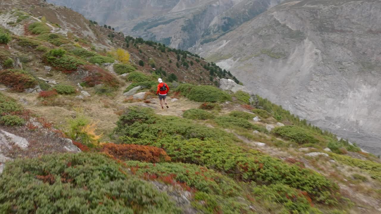 无人机拍摄的老人在高山山脊上奔跑，身后是冰川视频下载