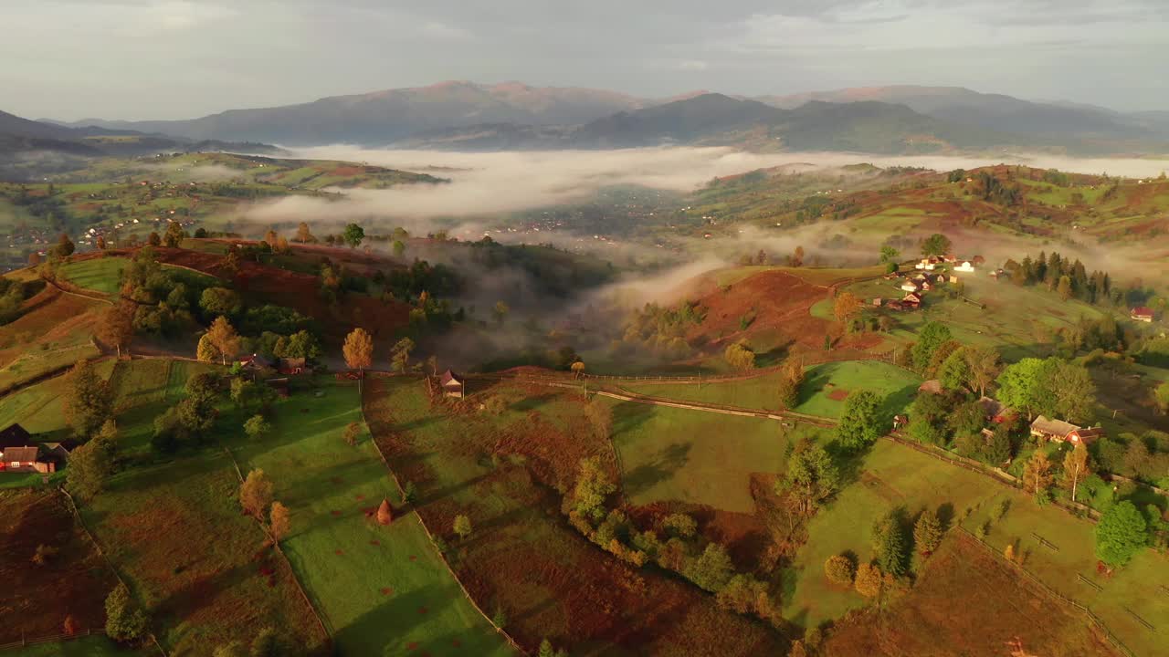 一架无人机飞过一个笼罩着晨雾的山村。视频下载