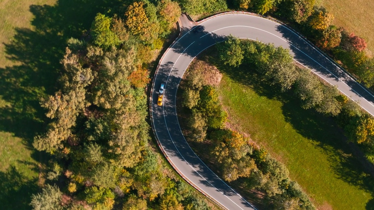 汽车行驶在德国秋天乡村弯弯曲曲的道路上-自上而下的航拍视频素材