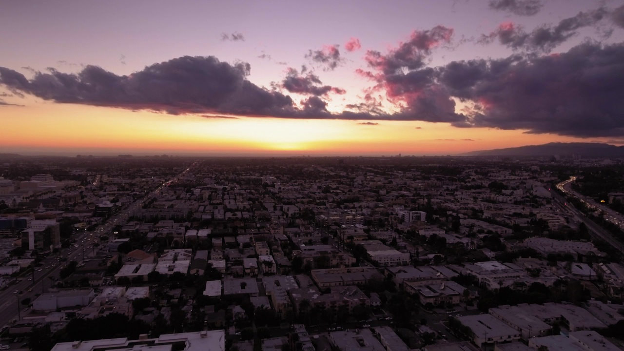 日落时，城市住宅建筑在橙色多云天空的映衬下，鸟瞰田园风光——加州卡尔弗城视频素材