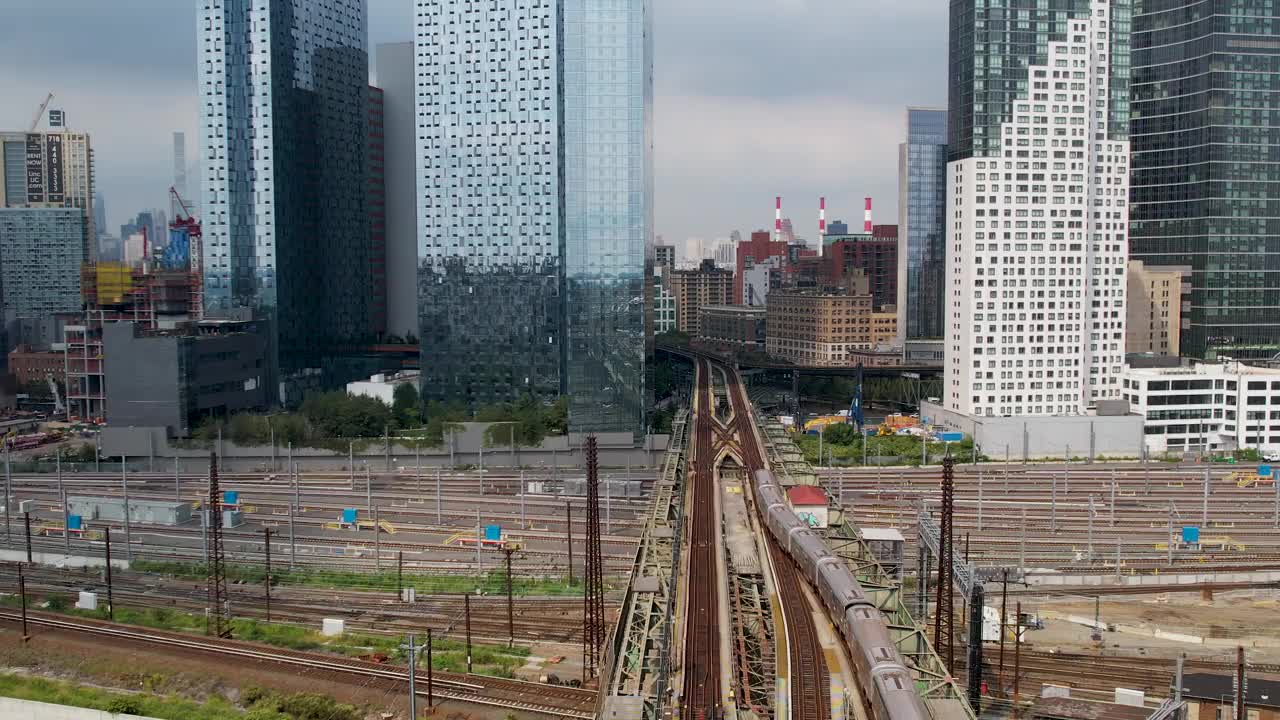 纽约皇后区长岛市摩天大楼之间的高架地铁线上行驶的火车的4k视频片段视频素材