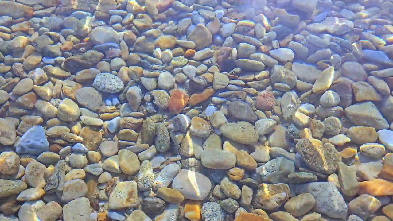 阳光照耀着岸边的水下鹅卵石视频素材