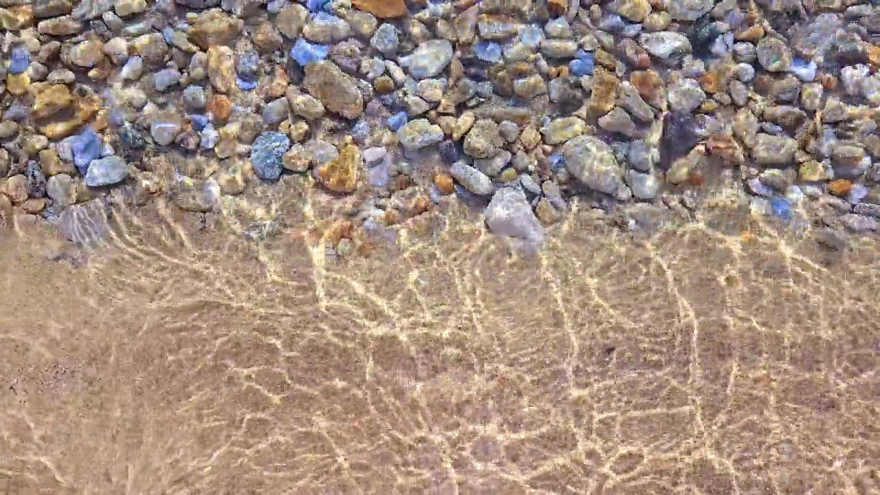沙滩上的沙子与水下的鹅卵石相遇视频素材