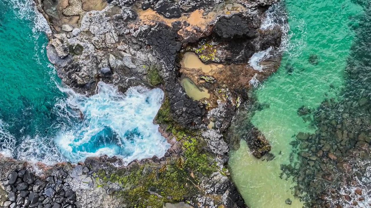 蓝色的海浪冲刷着遥远的夏威夷海滩海岸线上的火山岩视频下载