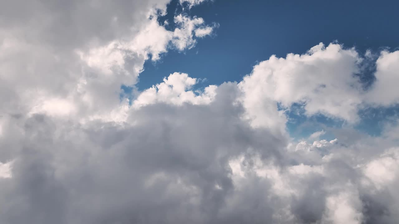 白色蓬松的云朵在清澈的蓝天上轻轻地移动，这是一幅风景如画的时间流逝图。视频素材