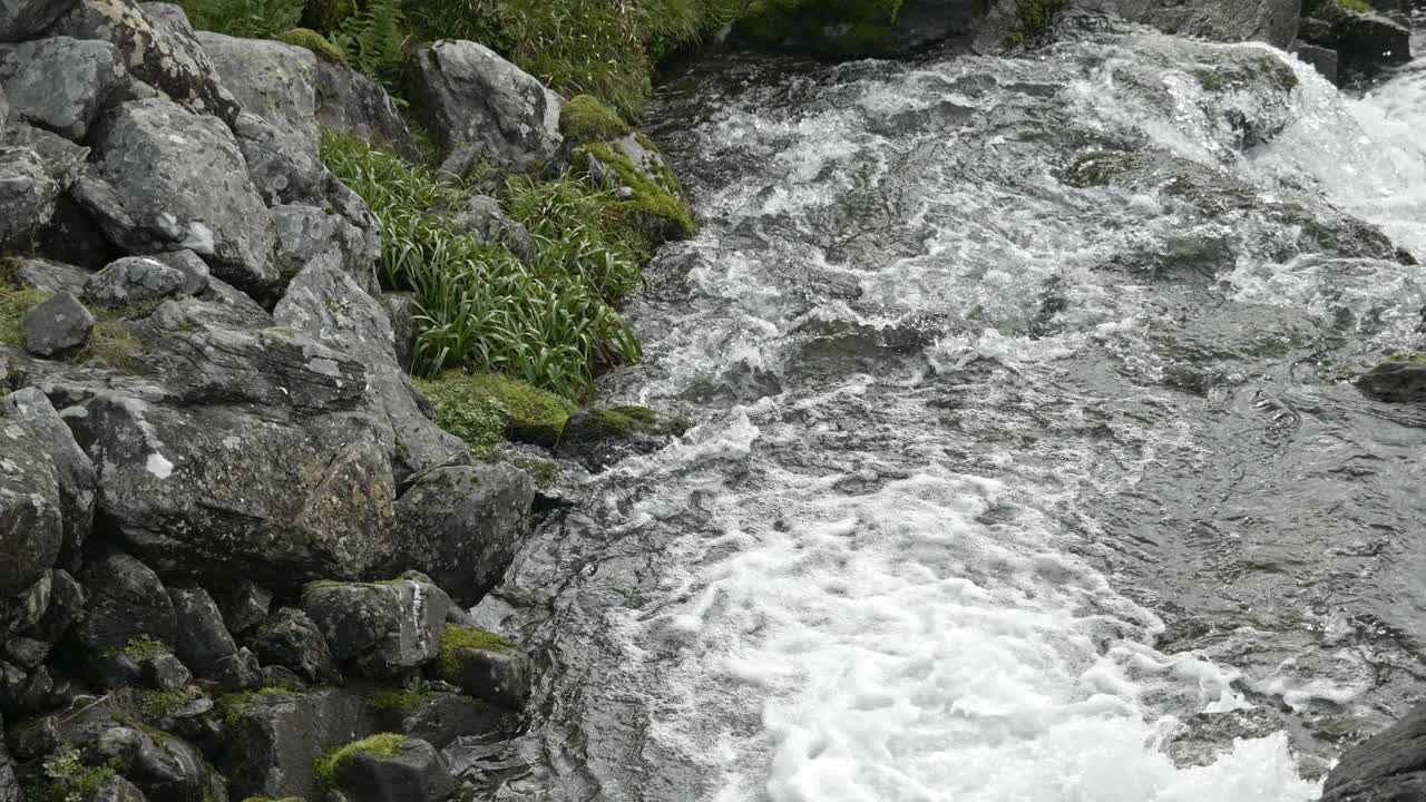 冒着泡沫的山间溪流迅速流过岩石地带。视频素材