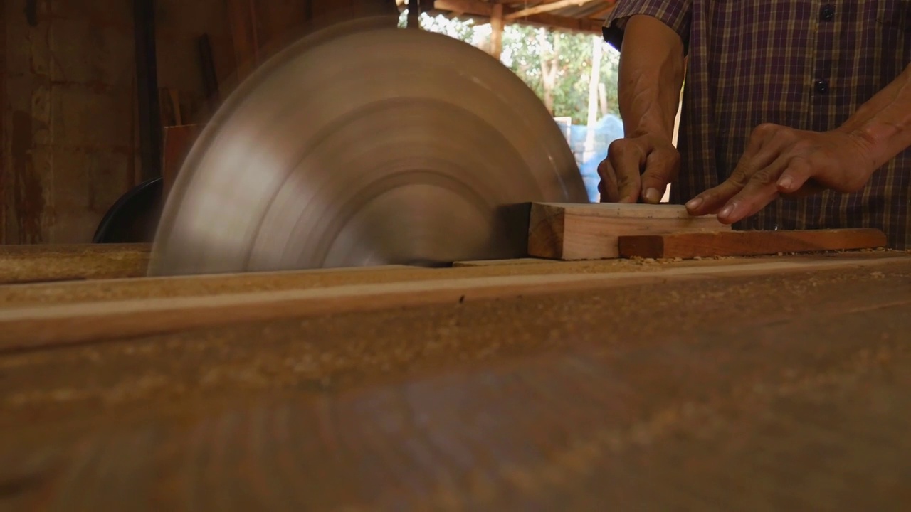 木匠用圆锯工作，电锯片，木匠的手切割木材视频素材