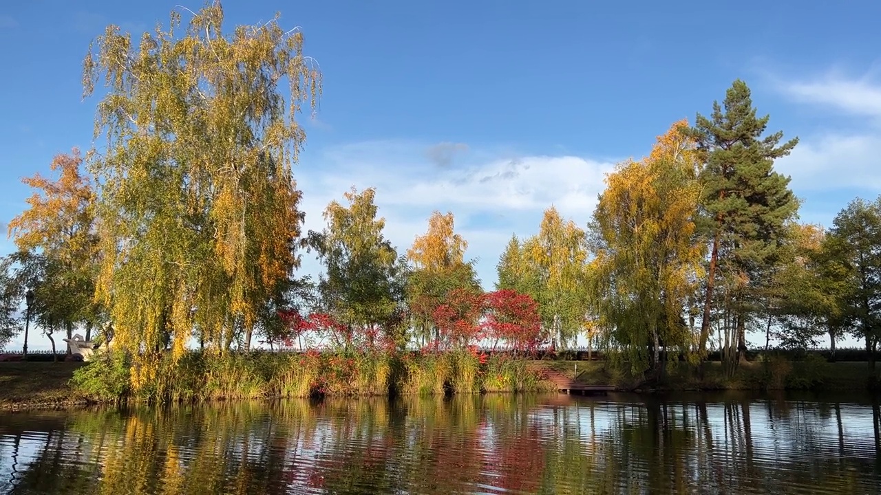 秋天的公园风景秀丽，五颜六色的树木树叶倒映在湖水中。视频素材