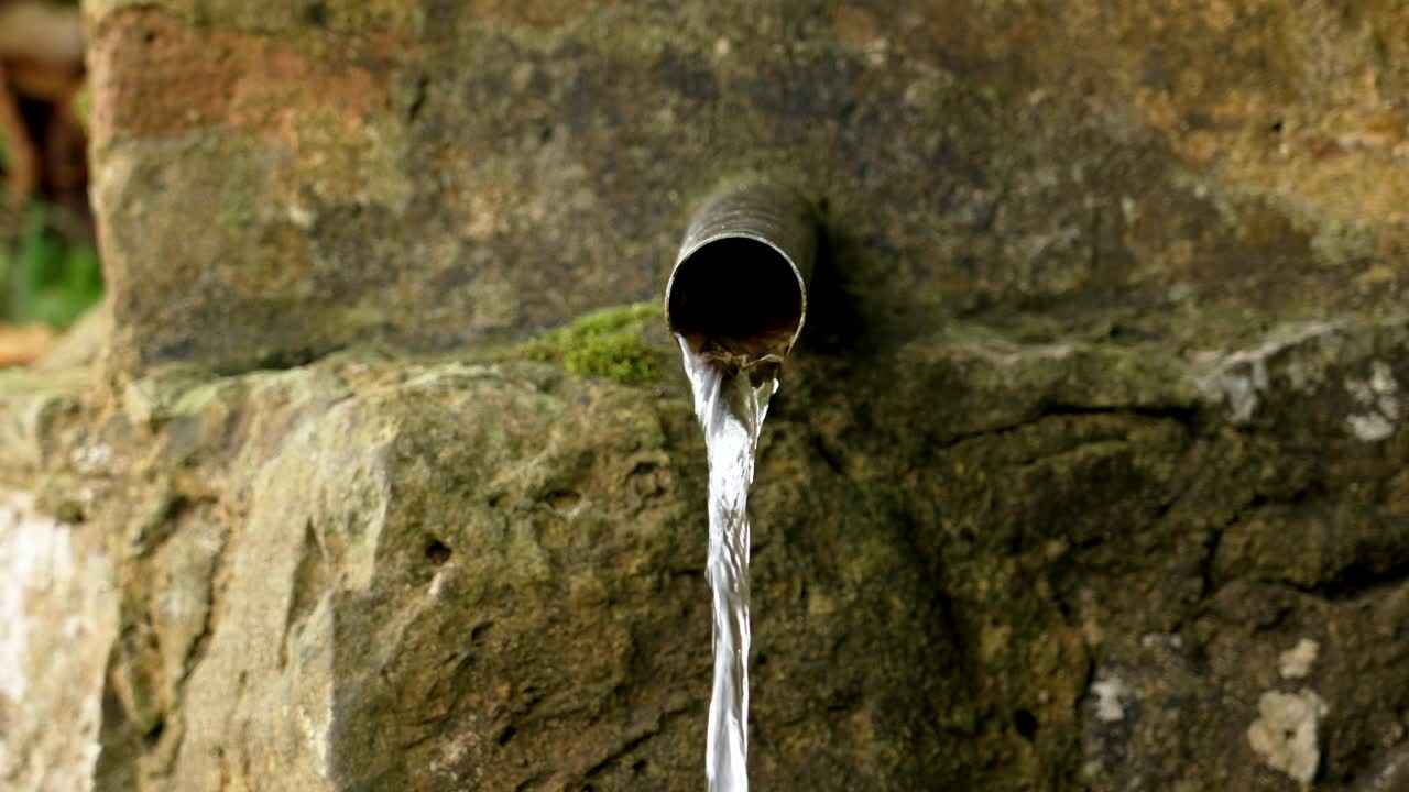 生活水源水晶般清澈的饮用水在岩石中近距离从钢管流出。生态系统概念视频素材