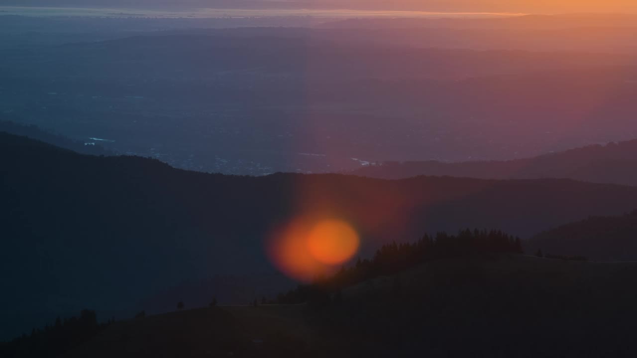 黑暗的松林被明亮的夕阳照亮。鸟瞰山野中五彩缤纷的日落。美丽的自然景观视频素材